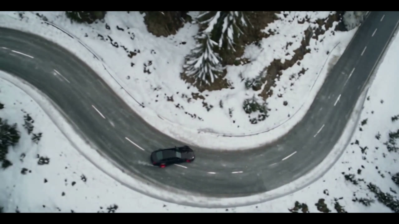 Aerial view of a winding snow-lined mountain road